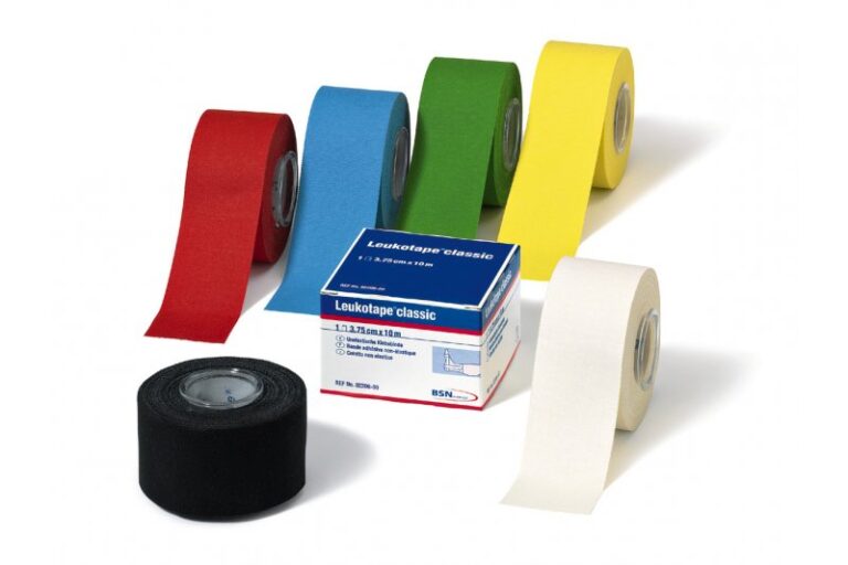 Verschiedene Rollen von Leukotape in den Farben Rot, Blau, Grün, Gelb und Weiß, daneben eine Verpackung mit Produktinformationen.